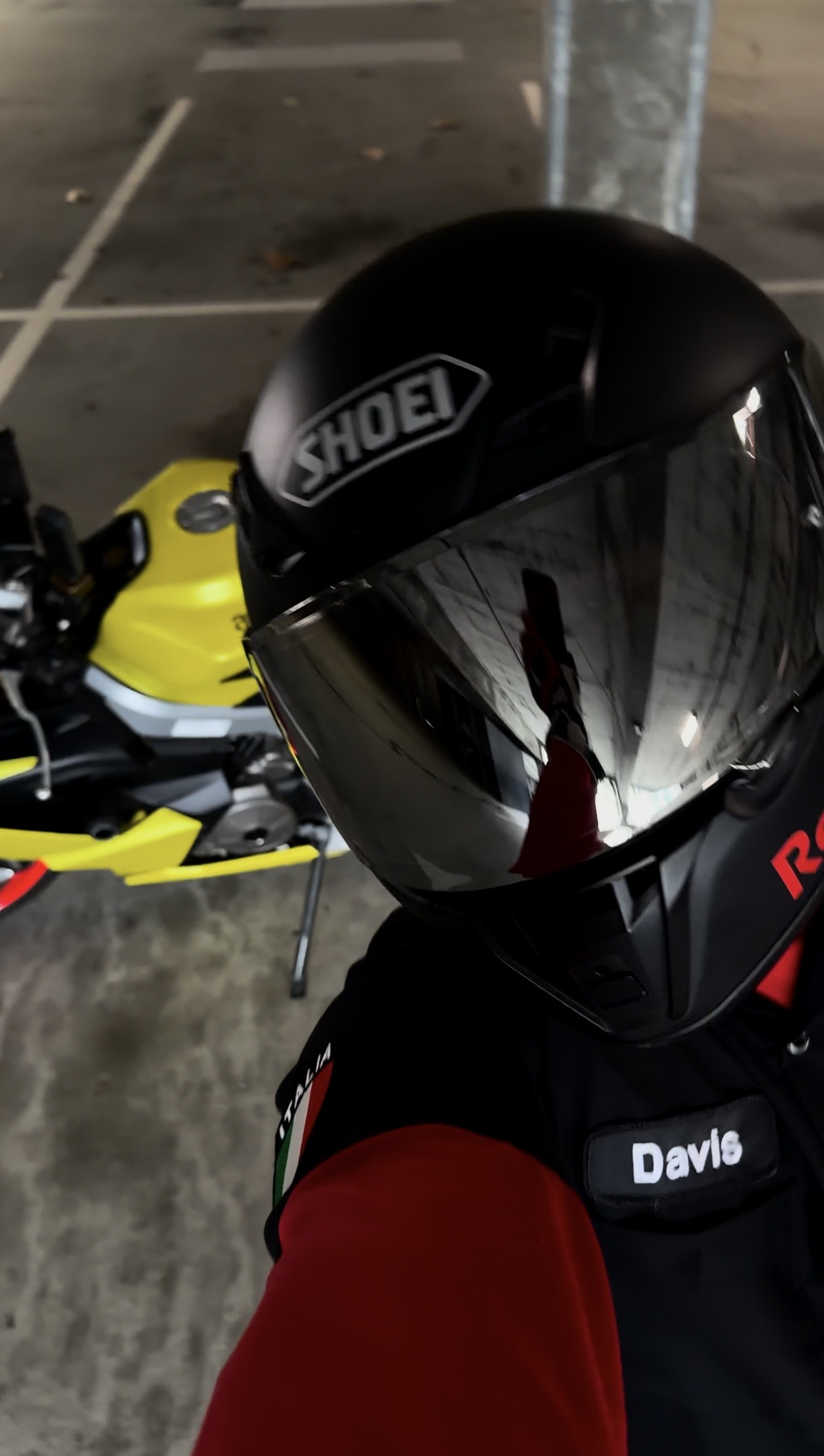 Close-up of rider in Shoei helmet with reflective visor and Aprilia racing gear