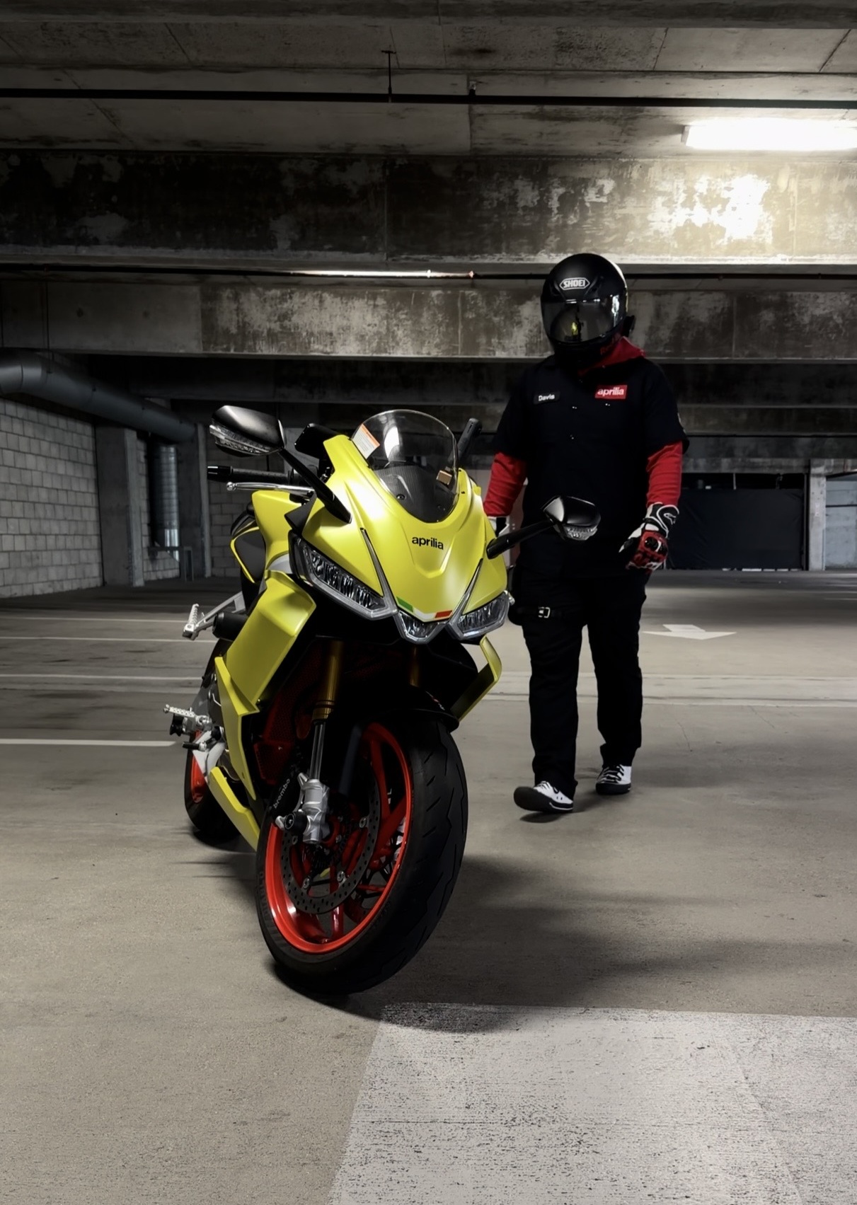 Yellow Aprilia RS660 with rider in underground parking garage